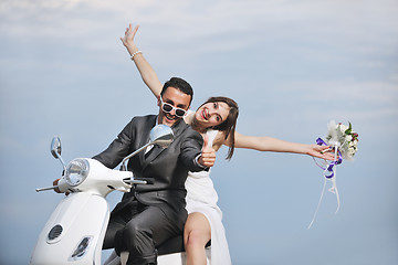 Image showing just married couple on the beach ride white scooter