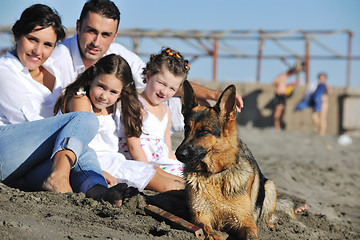 Image showing happy family playing with dog on beach