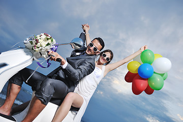 Image showing just married couple on the beach ride white scooter