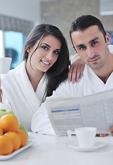 Image showing Happy couple reading the newspaper in the kitchen at breakfast