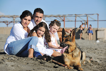 Image showing happy family playing with dog on beach