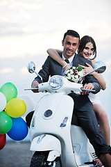 Image showing just married couple on the beach ride white scooter