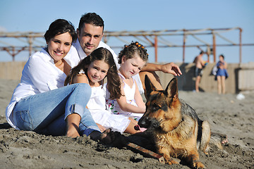 Image showing happy family playing with dog on beach