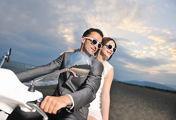 Image showing just married couple on the beach ride white scooter