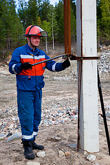 Image showing Electrician in blue overalls makes switching