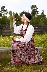 Image showing Girl in national costume paints a spinning wheel