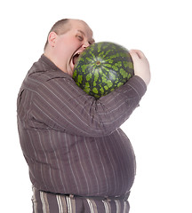 Image showing Obese man biting a watermelon