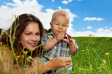 Image showing infant sniffing the flower