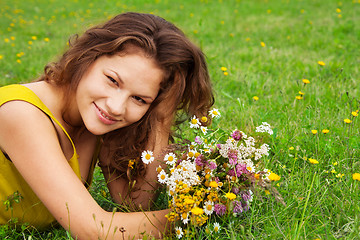 Image showing beautiful girl laying on grass with bouquet