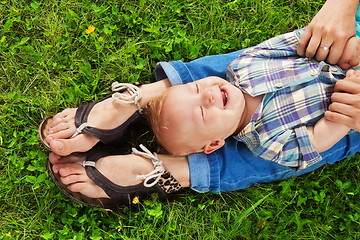 Image showing laughing kid laying on mommy's legs