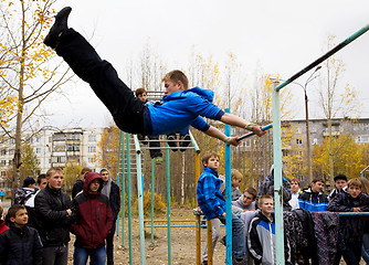 Image showing Young guys compete on the horizontal  bar