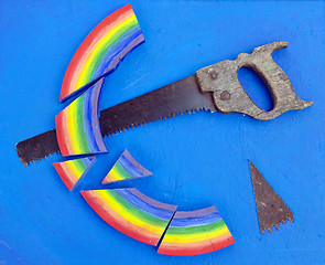 Image showing Concept rainbow cut with hand saw blue background 