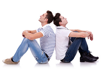 Image showing two young casual men sitting back to back 