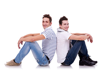 Image showing two young casual men sitting back to back 