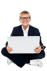 Image showing Cheerful young kid sitting on the floor with a laptop