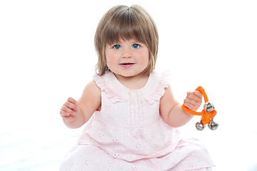 Image showing Healthy baby girl sitting on floor playing with rattle