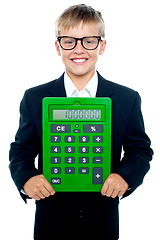 Image showing Bright young kid holding large green calculator