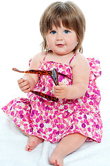 Image showing Baby girl sitting with shades in her hand