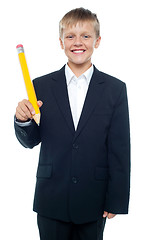 Image showing Cheerful young boy holding giant sized yellow pencil