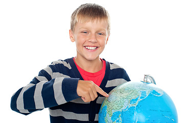 Image showing Cute little boy pointing out a continent on the globe