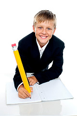 Image showing Charming school boy writing his assignment