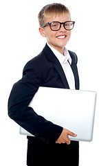 Image showing Bespectacled young boy carrying a laptop