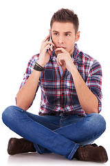 Image showing pensive man sitting and talking on the phone