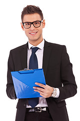 Image showing business man wearing glasses is writing  on clipboard 