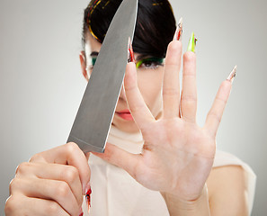 Image showing woman sharpening her nails with knife