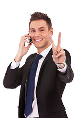 Image showing business man making victory sign on phone