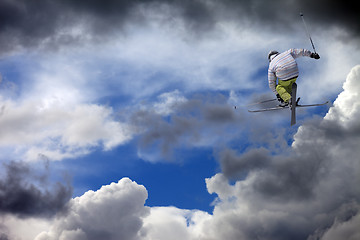 Image showing Freestyle ski jumper with crossed skis against cloudy sky