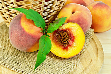 Image showing Peaches with leaves and a basket on board