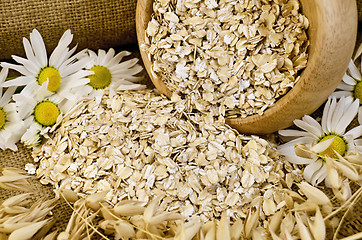 Image showing Oat flakes in a wooden bowl with chamomiles