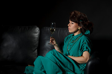 Image showing Beautiful girl sitting on a sofa with glass of wine