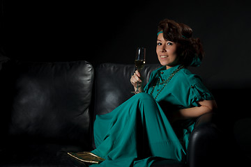 Image showing Beautiful girl sitting on a sofa with glass of wine
