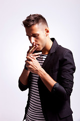 Image showing young fashion guy lighting his cigarette 
