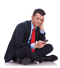 Image showing pensive young business man is reading a text message