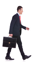 Image showing side view business man holding brief case and walking 