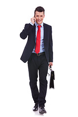 Image showing Business man with suitcase walking and talking on phone