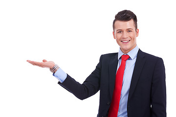 Image showing  young man in a suit presenting or holding something 