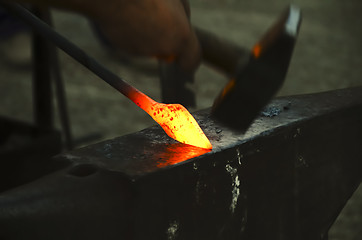 Image showing blacksmith forging a metal pin 