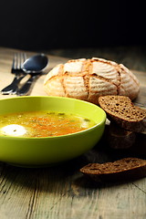 Image showing Poached egg with chicken broth in a green plate.