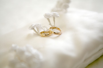 Image showing Two wedding rings with white flower in the background, wedding p