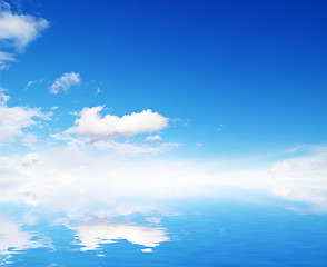 Image showing white fluffy clouds with rainbow in the blue sky