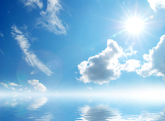 Image showing white fluffy clouds with rainbow in the blue sky