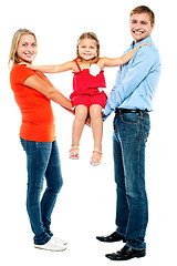 Image showing Baby girl sitting on outstretched arms of her parents