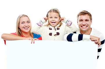 Image showing Young beautiful family behind white blank ad board