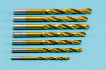 Image showing various size golden drill bits on blue 