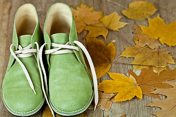 Image showing pair of green leather boots and yellow leaves