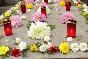 Image showing flowers and candles on a grave